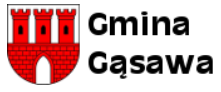 Herb gminy Gąsawa przedstawia w polu srebrnym tarczy herbowej czerwony mur z otwartą bramą i trzema blankowanymi czerwonymi wieżami. Każda z wież ma jedno okno.